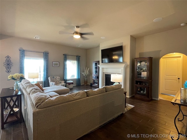 2613 W Van Buren Ct, Broken Arrow, OK 74011 - living room with arched walkways, dark wood-type flooring, a ceiling fan, a fireplace, and baseboards