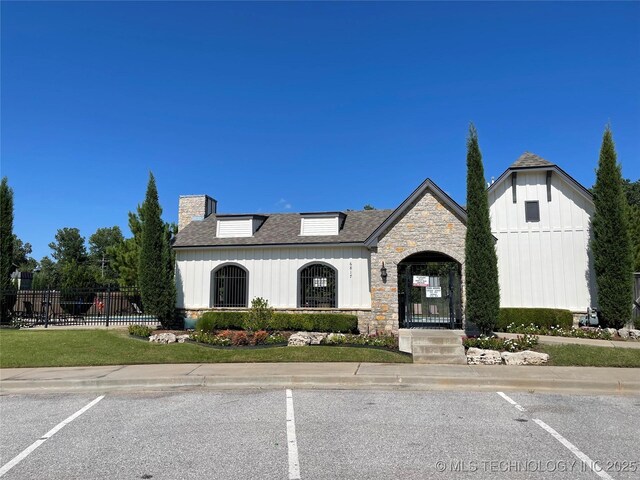 2613 W Van Buren Ct, Broken Arrow, OK 74011 - view of front of house featuring stone siding, uncovered parking, a chimney, and board and batten siding