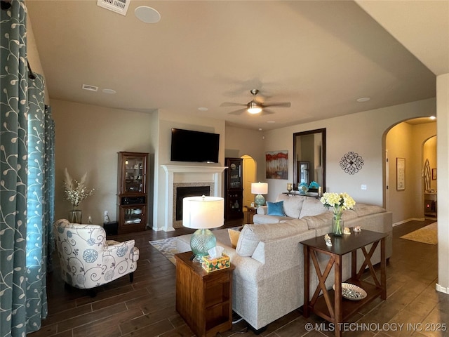 2613 W Van Buren Ct, Broken Arrow, OK 74011 - living room featuring arched walkways, a ceiling fan, dark wood-style floors, a fireplace, and baseboards