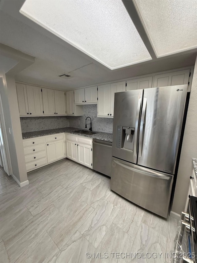 2800 E Seattle St, Broken Arrow, OK 74014 - kitchen with stainless steel appliances, a sink, baseboards, dark stone counters, and a textured ceiling