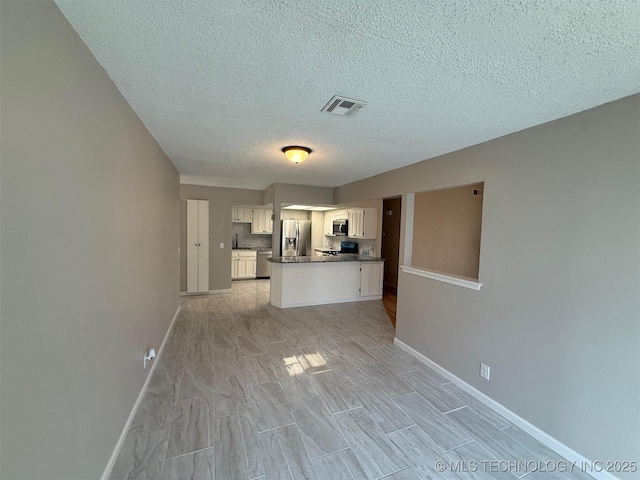 2800 E Seattle St, Broken Arrow, OK 74014 - kitchen featuring stainless steel appliances, dark countertops, a textured ceiling, white cabinetry, and baseboards