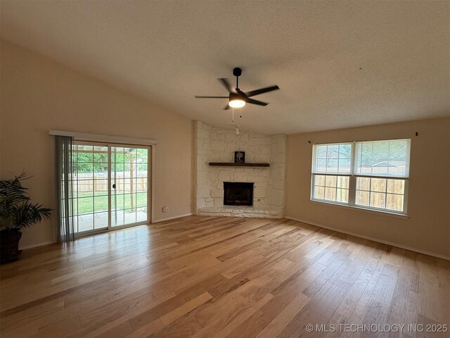 2800 E Seattle St, Broken Arrow, OK 74014 - unfurnished living room featuring ceiling fan, a textured ceiling, vaulted ceiling, light wood finished floors, and a fireplace
