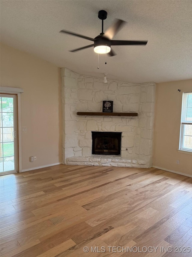 2800 E Seattle St, Broken Arrow, OK 74014 - unfurnished living room with lofted ceiling, a textured ceiling, a ceiling fan, wood finished floors, and a stone fireplace