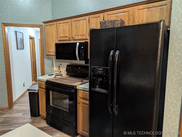 11309 S 107th E Ave, Bixby, OK 74008 - kitchen featuring black appliances, wood finished floors, wallpapered walls, and brown cabinetry