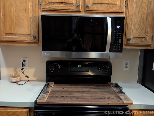 11309 S 107th E Ave, Bixby, OK 74008 - detailed view of stainless steel microwave, black range with electric cooktop, brown cabinetry, and light countertops