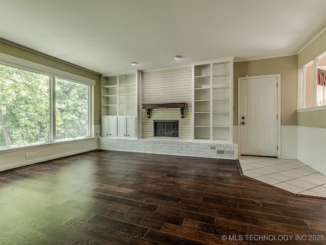 406 Sequoyah Trl, Norman, OK 73071 - unfurnished living room with hardwood / wood-style floors, built in shelves, a brick fireplace, healthy amount of natural light, and crown molding