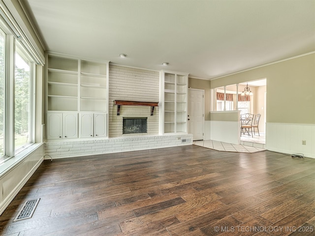 406 Sequoyah Trl, Norman, OK 73071 - unfurnished living room featuring a chandelier, hardwood / wood-style flooring, plenty of natural light, built in shelves, and a wainscoted wall