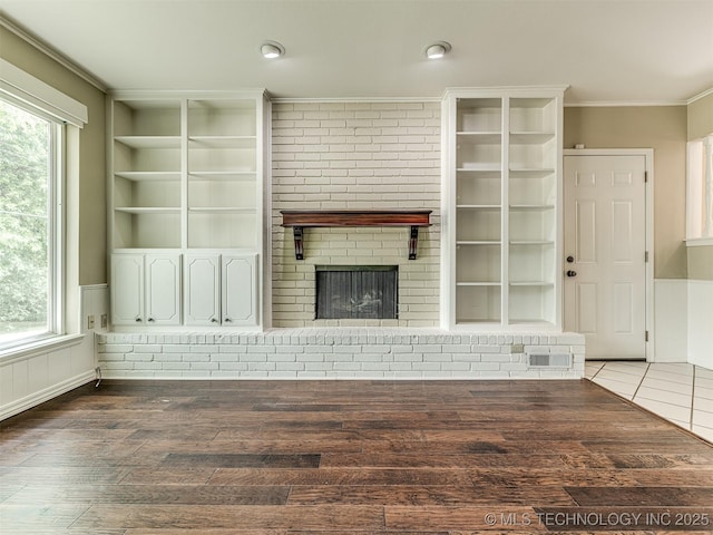 406 Sequoyah Trl, Norman, OK 73071 - unfurnished living room featuring a brick fireplace, ornamental molding, built in features, wood finished floors, and wainscoting