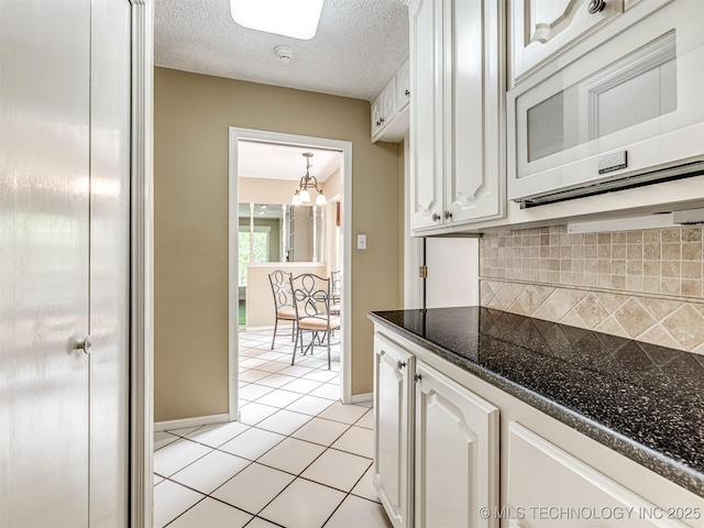 406 Sequoyah Trl, Norman, OK 73071 - kitchen with white microwave, white cabinetry, tasteful backsplash, light tile patterned floors, and baseboards