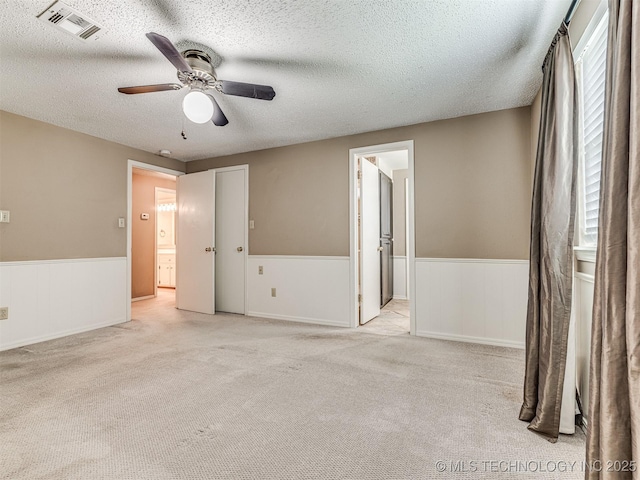 406 Sequoyah Trl, Norman, OK 73071 - spare room with wainscoting, light carpet, ceiling fan, and a textured ceiling
