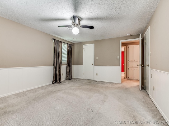 406 Sequoyah Trl, Norman, OK 73071 - carpeted spare room with wainscoting, a ceiling fan, and a textured ceiling