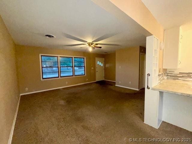 1714 E 11th St, Okmulgee, OK 74447 - unfurnished living room with dark carpet, a ceiling fan, and baseboards