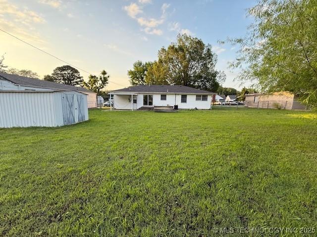 1714 E 11th St, Okmulgee, OK 74447 - back of house at dusk with a yard and an outbuilding