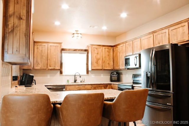 17 Zachary Taylor, Durant, OK 74701 - kitchen with stainless steel appliances, a sink, light brown cabinets, a peninsula, and a kitchen bar
