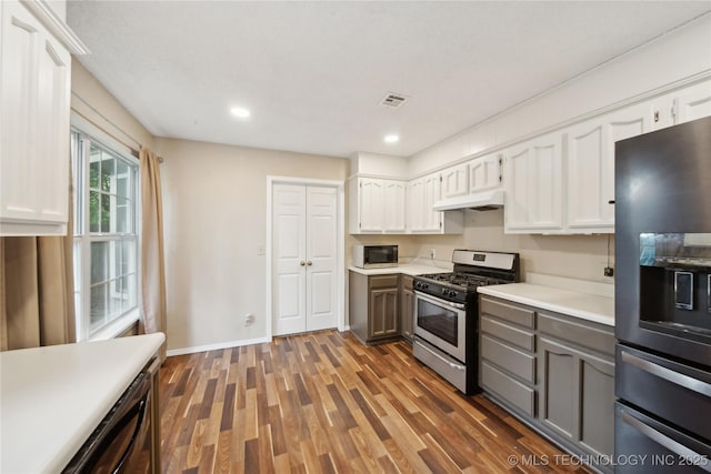 9306 S 94th E Ave, Tulsa, OK 74133 - kitchen with appliances with stainless steel finishes, under cabinet range hood, light countertops, white cabinets, and wood finished floors