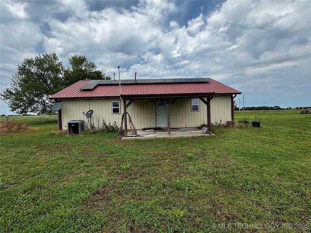 26230 Ash Rd, Boynton, OK 74422 - back of property featuring a lawn, metal roof, central air condition unit, solar panels, and board and batten siding