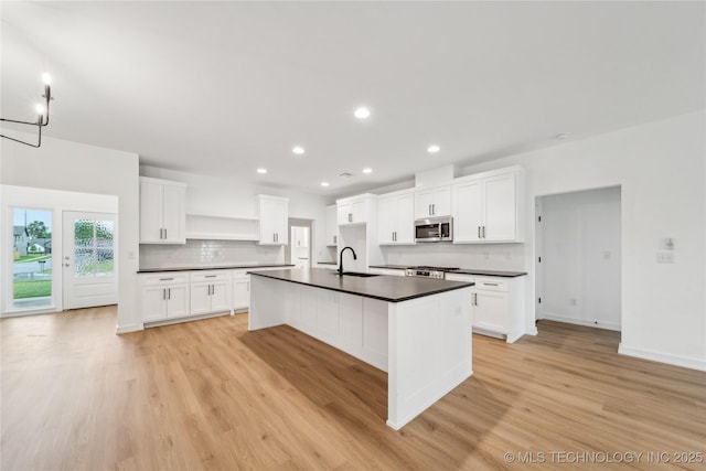 2504 W Birmingham St, Broken Arrow, OK 74011 - kitchen with stainless steel microwave, open shelves, dark countertops, a sink, and light wood-style flooring