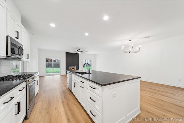 2504 W Birmingham St, Broken Arrow, OK 74011 - kitchen featuring stainless steel appliances, a sink, dark countertops, light wood-style flooring, and a chandelier