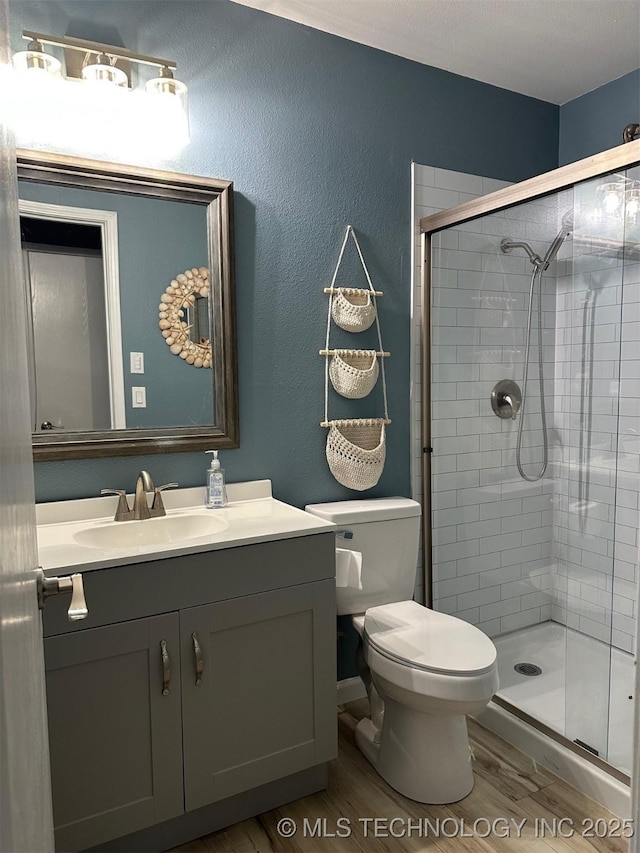 166 N Spruce Ave, Bartlesville, OK 74006 - bathroom featuring wood finished floors, a shower stall, toilet, vanity, and a textured wall