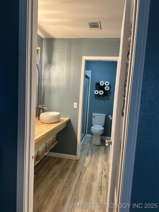 166 N Spruce Ave, Bartlesville, OK 74006 - full bath featuring wood finished floors, a stall shower, vanity, toilet, and a textured ceiling