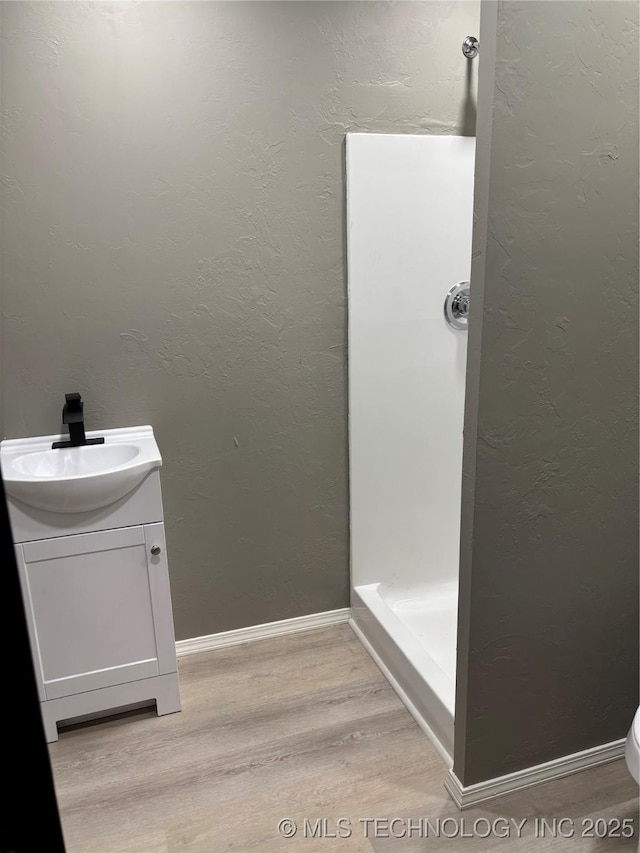 413 E 8th St, Cushing, OK 74023 - full bathroom with wood finished floors, vanity, a shower, toilet, and a textured wall