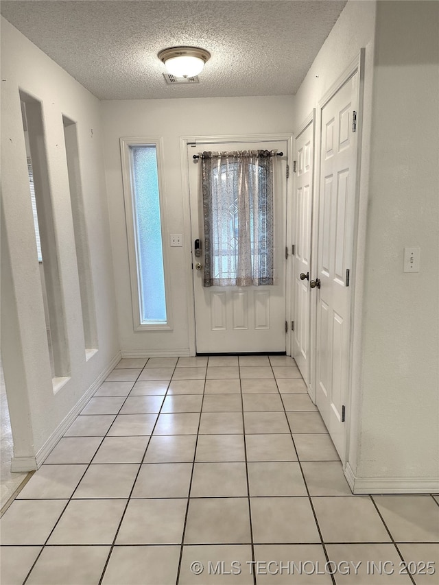 108 NW Division St, Red Oak, OK 74563 - foyer entrance with a textured ceiling, light tile patterned floors, and baseboards