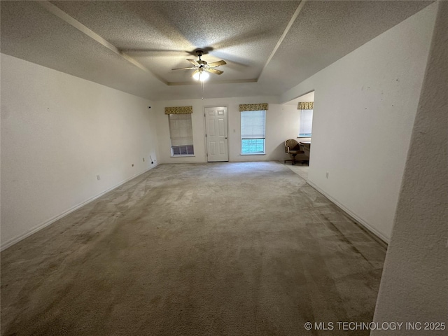 108 NW Division St, Red Oak, OK 74563 - unfurnished living room with a ceiling fan, a textured ceiling, a raised ceiling, carpet floors, and baseboards