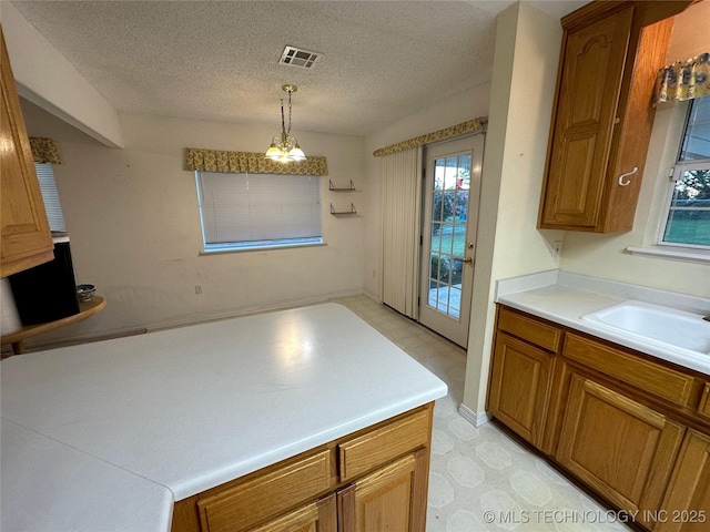 108 NW Division St, Red Oak, OK 74563 - kitchen featuring brown cabinets, plenty of natural light, light flooring, and a textured ceiling