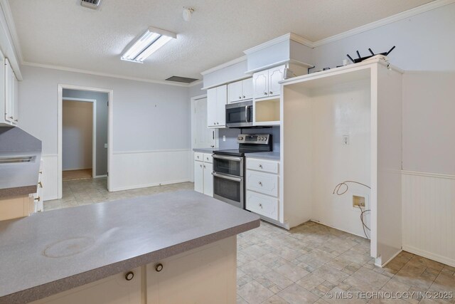901 Christy, Calera, OK 74730 - kitchen with appliances with stainless steel finishes, white cabinetry, a wainscoted wall, ornamental molding, and a textured ceiling