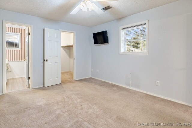 901 Christy, Calera, OK 74730 - unfurnished bedroom featuring light carpet, a walk in closet, baseboards, a textured ceiling, and ceiling fan