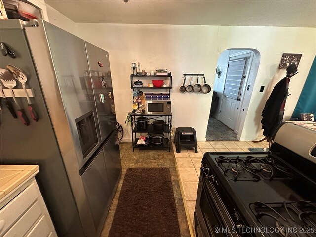 661 12th NW, Ardmore, OK 73401 - kitchen featuring gas stove, stainless steel refrigerator with ice dispenser, and light tile patterned flooring