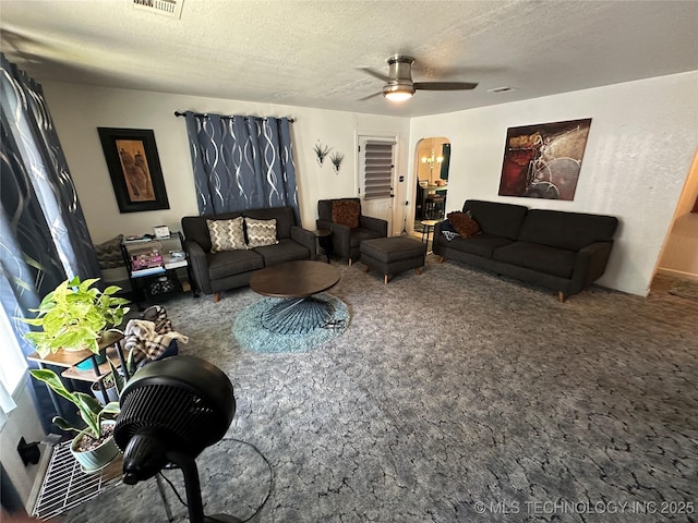 661 12th NW, Ardmore, OK 73401 - carpeted living area with arched walkways, a ceiling fan, and a textured ceiling