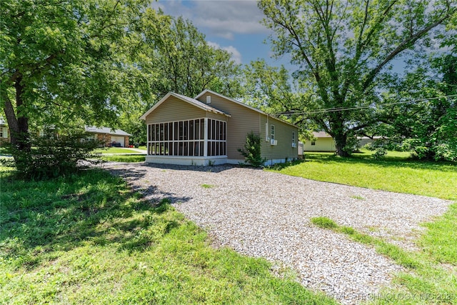 609 E Tejon Ave, Bristow, OK 74010 - rear view of house featuring a sunroom, driveway, and a lawn