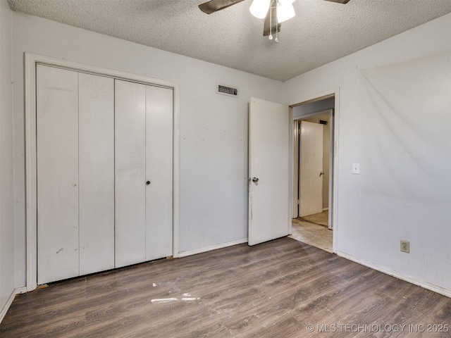 12641 S 281st E Ave, Coweta, OK 74429 - unfurnished bedroom featuring wood finished floors, a textured ceiling, a closet, baseboards, and a ceiling fan