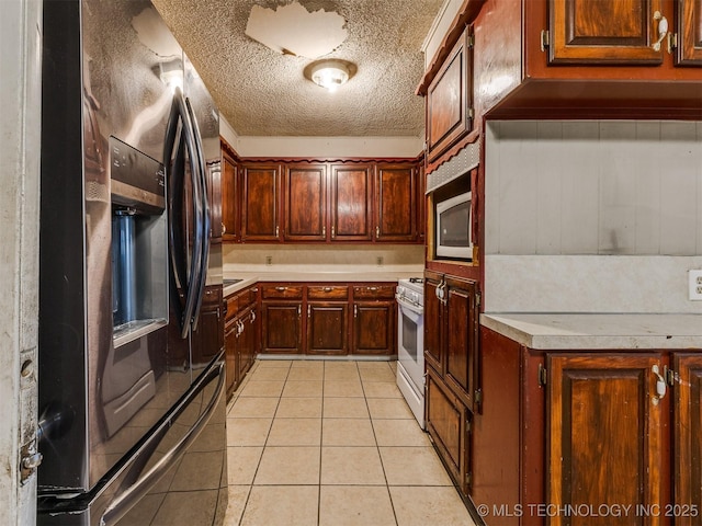 12641 S 281st E Ave, Coweta, OK 74429 - kitchen with fridge with ice dispenser, white gas stove, light countertops, light tile patterned flooring, and a textured ceiling