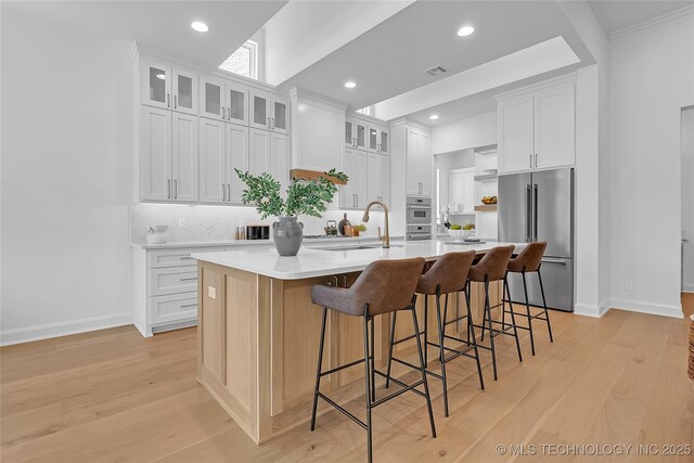1227 N 71st Pl, Broken Arrow, OK 74014 - kitchen featuring appliances with stainless steel finishes, decorative backsplash, a large island with sink, white cabinetry, and recessed lighting