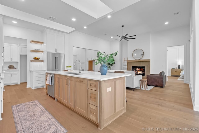 1227 N 71st Pl, Broken Arrow, OK 74014 - kitchen featuring stainless steel appliances, a sink, a skylight, a glass covered fireplace, and light wood-style floors