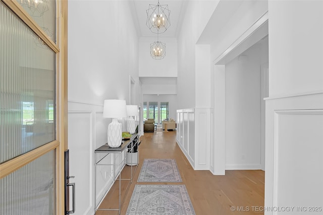 1227 N 71st Pl, Broken Arrow, OK 74014 - hallway with a chandelier, a decorative wall, wood finished floors, wainscoting, and a high ceiling