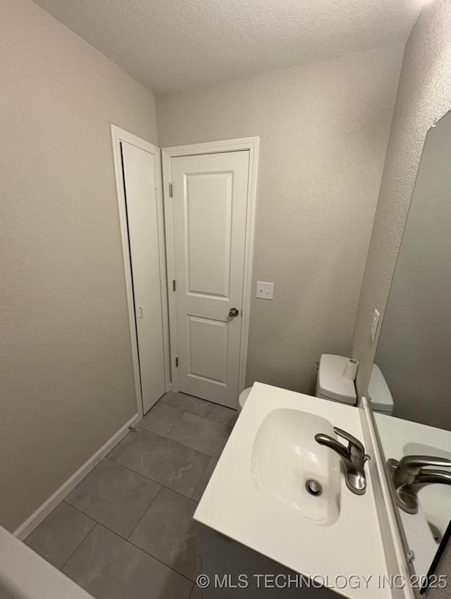 6837 E King Pl, Tulsa, OK 74115 - bathroom featuring vanity, a textured ceiling, tile patterned flooring, toilet, and baseboards