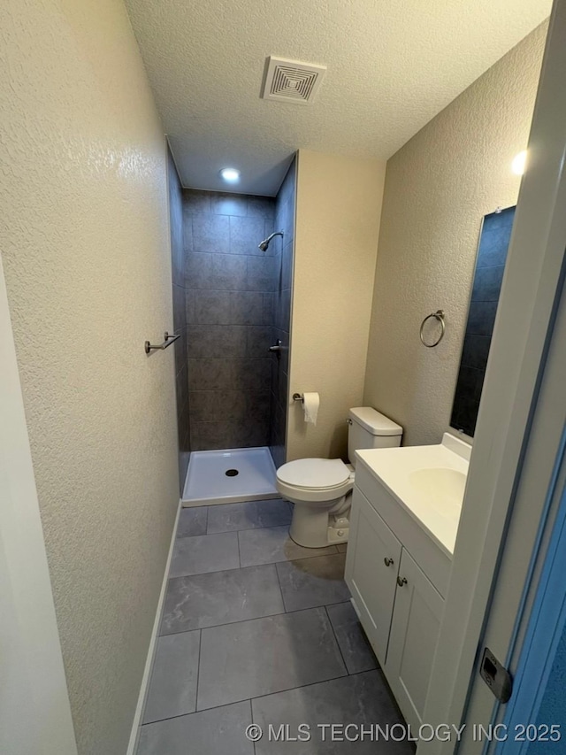 6837 E King Pl, Tulsa, OK 74115 - full bathroom featuring a textured wall, a tile shower, vanity, toilet, and a textured ceiling