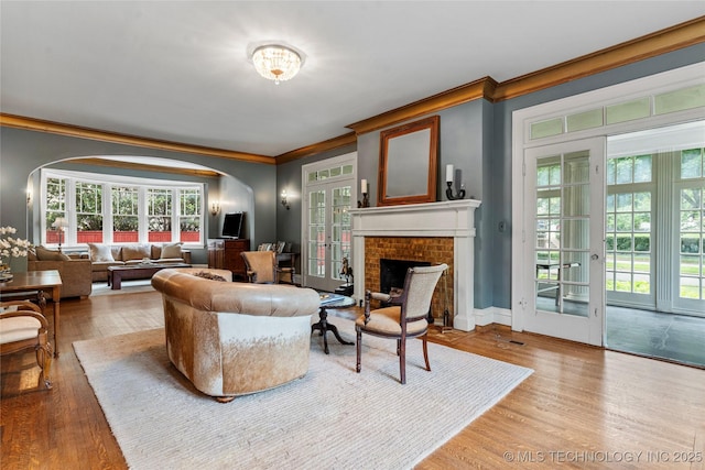 319 E 21st St, Tulsa, OK 74114 - living area with ornamental molding, arched walkways, a fireplace, healthy amount of natural light, and wood finished floors