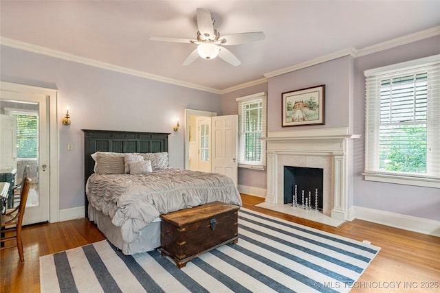 319 E 21st St, Tulsa, OK 74114 - bedroom featuring wood finished floors, multiple windows, a fireplace with flush hearth, baseboards, and crown molding