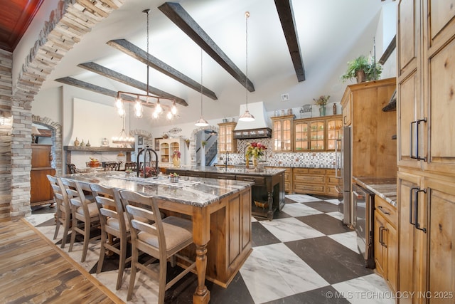 30907 E 68th St S, Broken Arrow, OK 74014 - kitchen with a kitchen island with sink, stainless steel refrigerator, light stone counters, and a kitchen breakfast bar