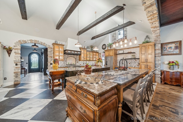 30907 E 68th St S, Broken Arrow, OK 74014 - kitchen featuring a spacious island, custom exhaust hood, high end refrigerator, arched walkways, and beamed ceiling