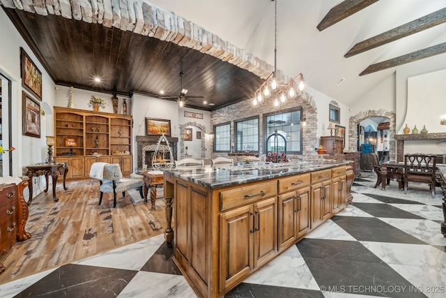 30907 E 68th St S, Broken Arrow, OK 74014 - kitchen with arched walkways, a warm lit fireplace, ceiling fan, open floor plan, and dark stone countertops
