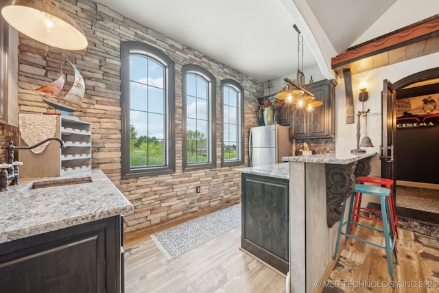 30907 E 68th St S, Broken Arrow, OK 74014 - kitchen featuring freestanding refrigerator, a sink, vaulted ceiling, a breakfast bar, and light wood finished floors