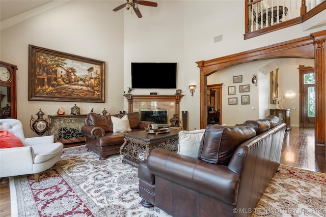 11406 69th E Pl, Bixby, OK 74008 - living room featuring arched walkways, wood finished floors, ceiling fan, a high end fireplace, and a high ceiling