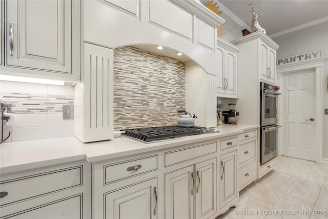 11406 69th E Pl, Bixby, OK 74008 - kitchen with stainless steel appliances, decorative backsplash, ornamental molding, light countertops, and white cabinets