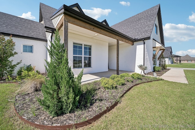 123 E 168th St, Glenpool, OK 74033 - view of property exterior with a yard, roof with shingles, a patio, and brick siding