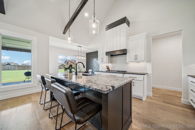 123 E 168th St, Glenpool, OK 74033 - kitchen with stainless steel gas stovetop, backsplash, white cabinetry, dark stone counters, and an island with sink